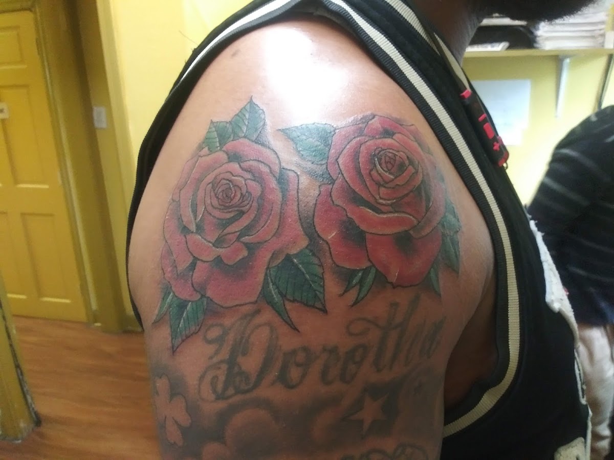Color rose tattoos with name script lettering on the shoulder