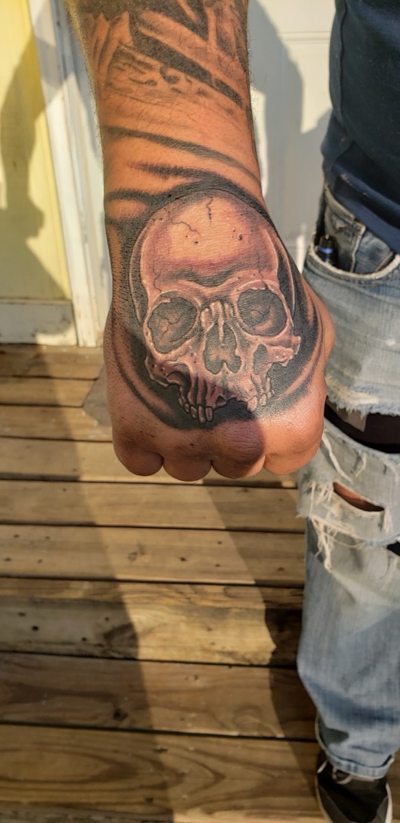 Black and grey skull tattoo on the back of the hand